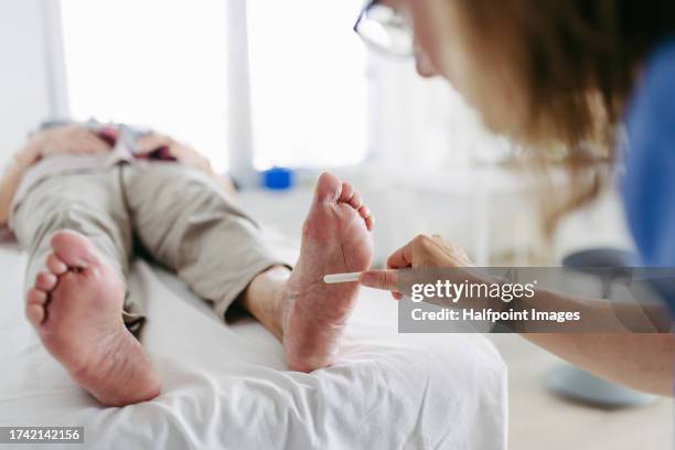 diabetologist testing for loss of sensation in a patient's feet. - diabetes feet stock pictures, royalty-free photos & images