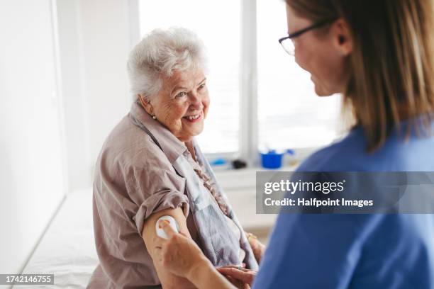 diabetologist applying a continuous glucose monitor sensor to senior patient's arm. - glucose stockfoto's en -beelden