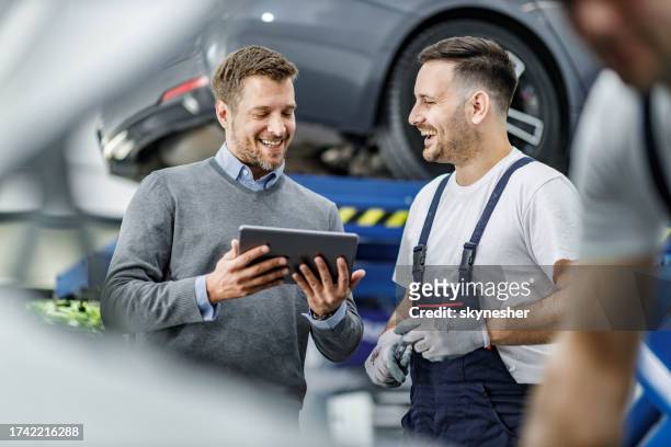 happy customer and auto mechanic using touchpad in a workshop. - garage stock pictures, royalty-free photos & images
