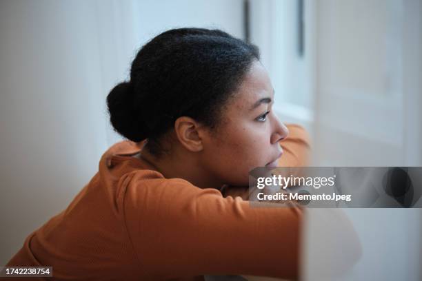 depression in teens. sad depressed african american teenage girl looking out window, feeling lonely, upset black woman at home. mental health of adolescents, teenage problems - pessimisme stock pictures, royalty-free photos & images