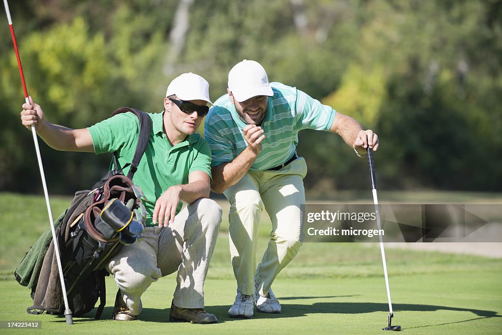Golfer And Caddy Contemplating A Putting shot
