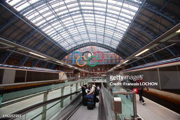 Voyageurs avec leurs bagages sur un quai de la gare de Saint-Pancras arborant les anneaux olympiques à Londres le 18 mai 2011.
