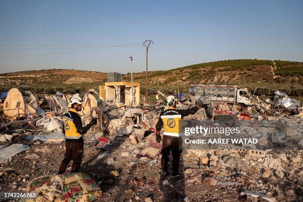 Members of the Syrian Civil Defence survey the area following a Russian air strike, at a camp for those displaced by conflict on the outskirts of the...