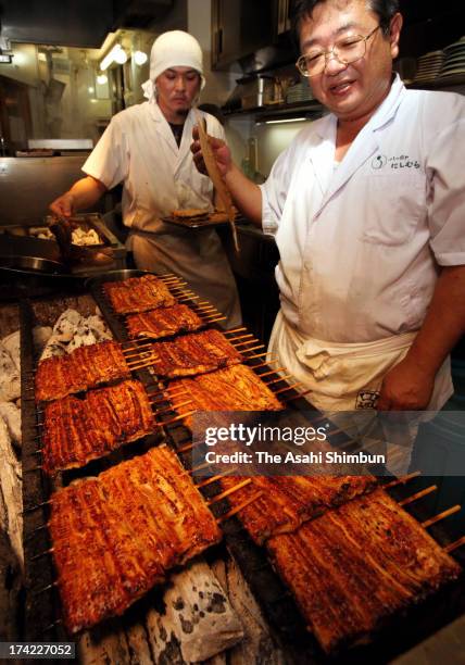 An eel chef cooks 'Kabayaki' eel at Yatsumeya Nishimura on July 22, 2013 in Tokyo, Japan. It is said that people eat eel on the Doyo-no-Ushi-no-Hi,...