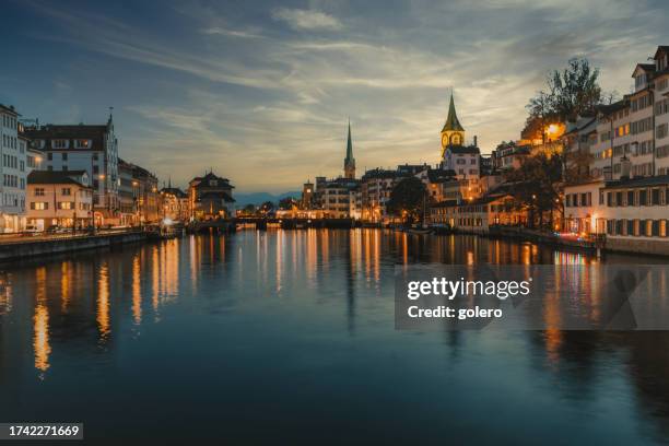 beleuchtetes stadtbild der altstadt zürich entlang des flusses zur blauen stunde - zürich stock-fotos und bilder