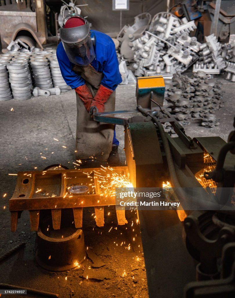 Factory Worker Using A Grinder To Grind Off Rough Edges On A Steel Part ...