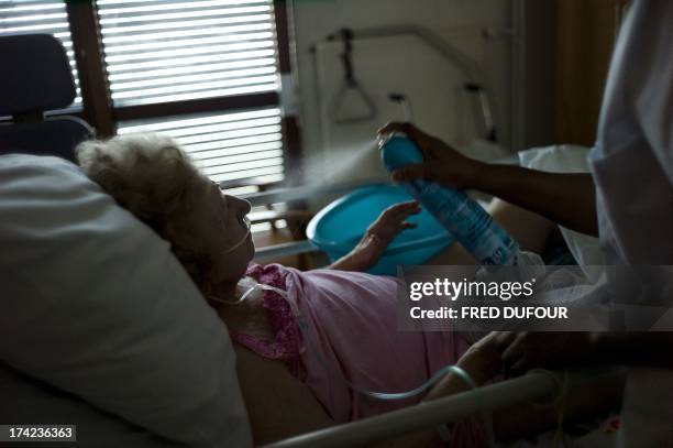 Nurse sprays water to cool off an old woman at the geriatric hospital of Argenteuil on July 22, 2013 as France swelters under a summer heatwave. AFP...