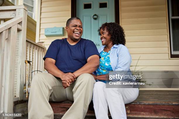 pareja negra madura hablando y riendo en el porche delantero - gente común y corriente fotografías e imágenes de stock
