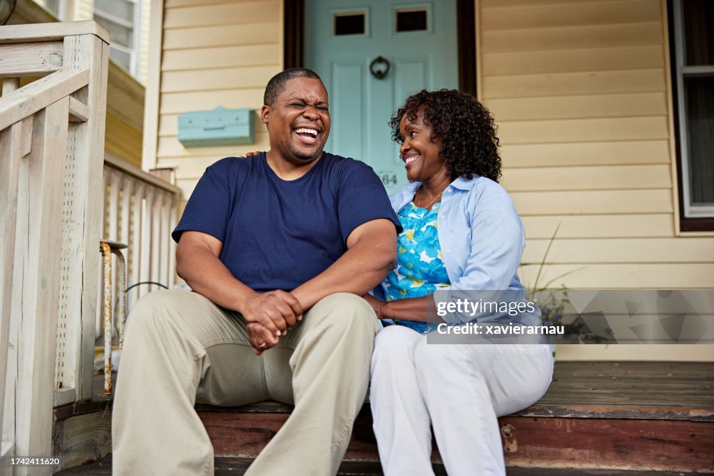 Mature Black couple talking and laughing on front porch