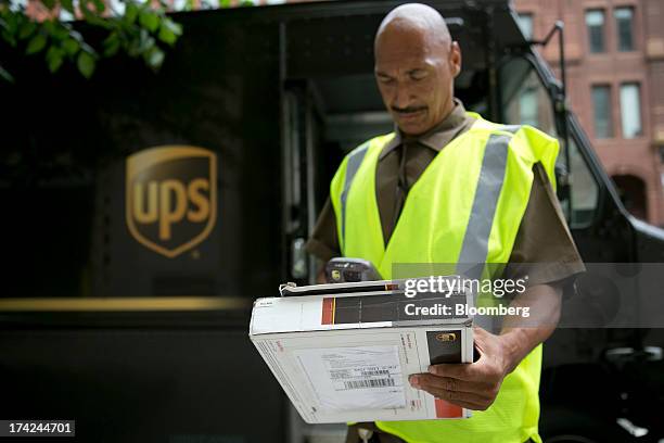 United Parcel Service Inc. Employee Eric Brooks scans a package while making a delivery in Washington, D.C., U.S., on Monday, July 22, 2013. UPS is...