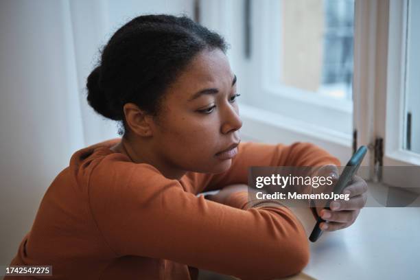 sad worried african american woman using smartphone at home, scrolling social media feeling depressed at mobile phone screen. social media depression, digital devices and mental health - générique photos et images de collection