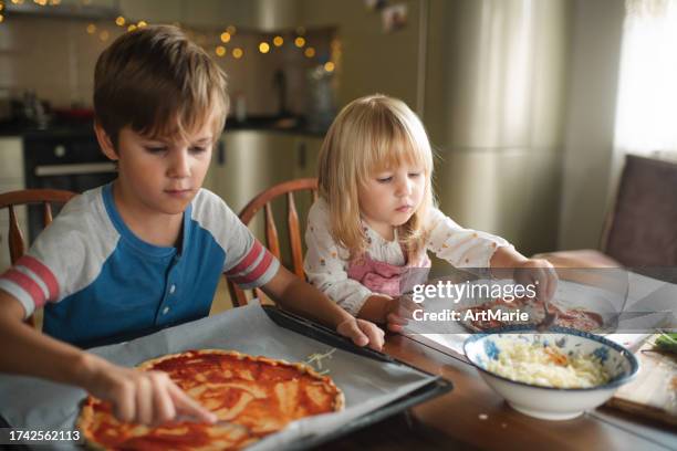 children making pizza at the kitchen - family with two children stock pictures, royalty-free photos & images