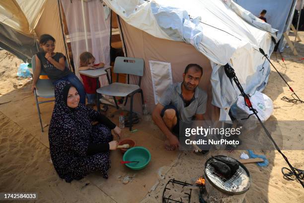 Palestinian children receive food between tents set up for Palestinians seeking refuge on the grounds of a United Nations Relief and Works Agency for...