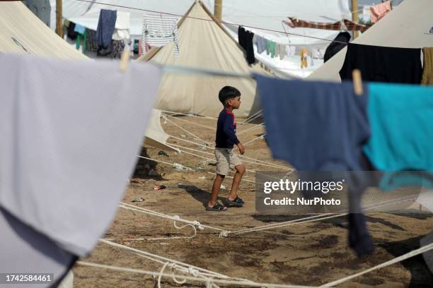 Palestinian children receive food between tents set up for Palestinians seeking refuge on the grounds of a United Nations Relief and Works Agency for...