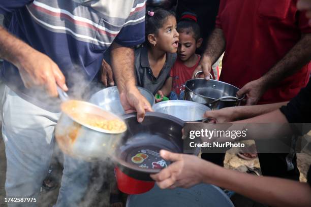 Palestinian children receive food between tents set up for Palestinians seeking refuge on the grounds of a United Nations Relief and Works Agency for...