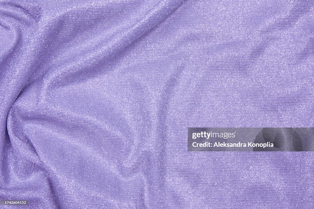Trendy 80s, 90s, 2000s Background of draped light purple fabric with silver lurex thread. Beautiful fashionable shiny fabric with a shiny thread for making clothes. Textile background texture.
