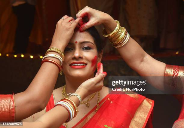 Hindu women apply 'sindhur', or vermillion powder, on each other after worshipping the idol of the Hindu goddess Durga on the last day of the Durga...