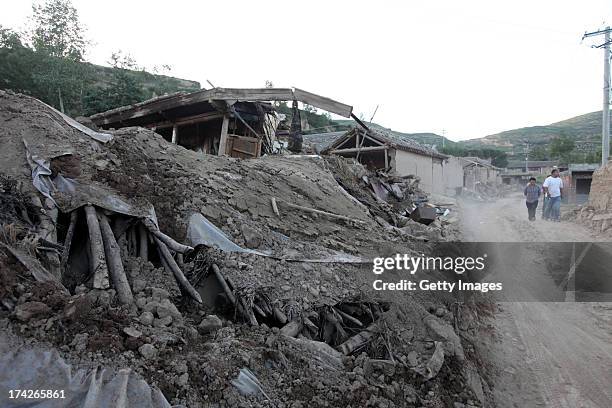Local residents walk past collapsed houses in Yongguang village on July 22, 2013 in Minxian, China. At least 89 people were killed and 5 others...