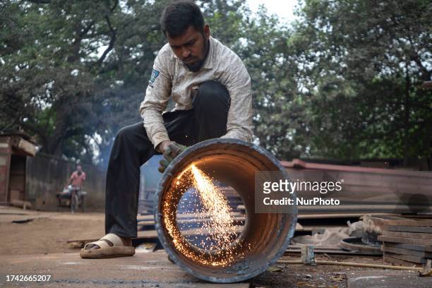 Workers weld to cut a part on steel structure with a blow torch at a workshop in Dhaka on October 23, 2023.