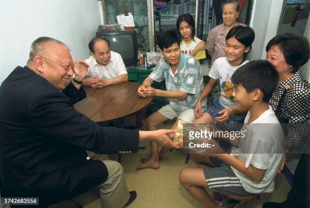 Hong Kong Chief Executive Tun Chee-hwa hands a present to an unidentified child in Hong Kong 04 august 2000. Tung was on a visit to low-income...