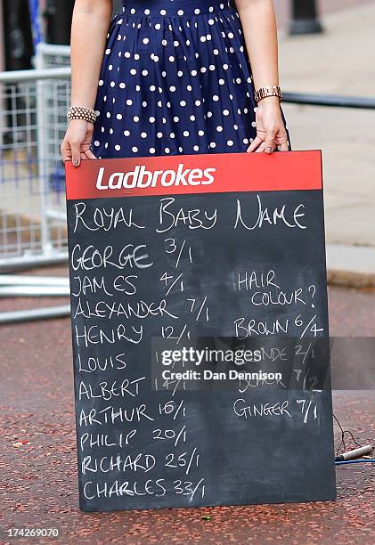 Woman holds a Ladbrokes board listing possible baby names to bet on as media gather outside Buckingham Palace to read the easel displaying the...