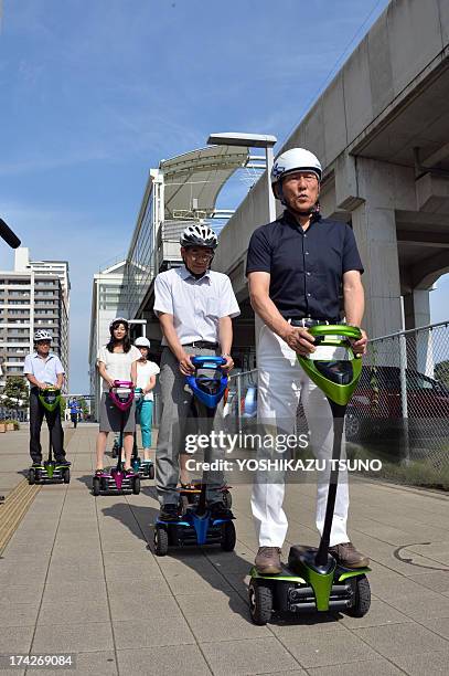 The mayor of Japan's Tsukuba City, Kenichi Ichihara , and Toyota Motor partner robot director Akifumi Tamaoki ride with city hall employees on...