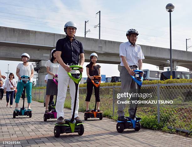 The mayor of Japan's Tsukuba City, Kenichi Ichihara , and Toyota Motor partner robot director Akifumi Tamaoki ride with city hall employees on...