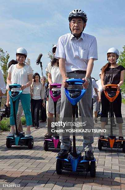 Toyota Motor partner robot director Akifumi Tamaoki and Tsukuba City Hall employees ride on Toyota's transport assistance robot, called the...