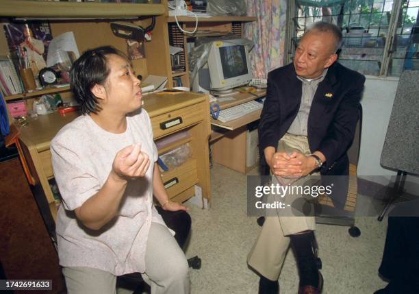 Hong Kong Chief Executive Tun Chee-hwa listens to an unidentified woman in Hong Kong 04 August 2000. Tung was on a visit to low-income families in...