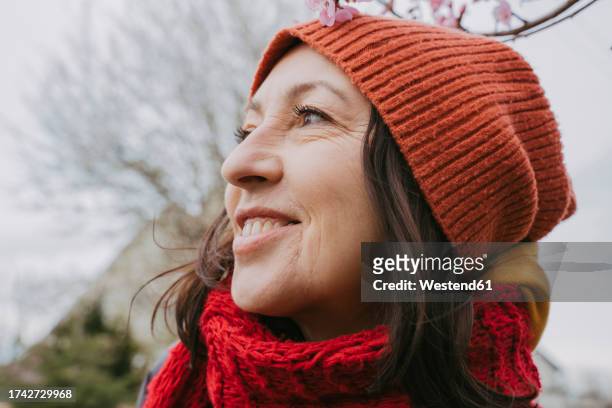 thoughtful woman wearing scarf and knit hat - mature woman winter stock pictures, royalty-free photos & images