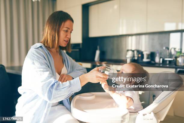 mother gives water to a baby - hand over mouth stock pictures, royalty-free photos & images