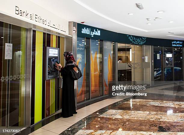 Customer uses an automated teller machine operated by Bank al Etihad beside a branch of Jordan Ahli Bank inside the Taj shopping mall in Amman,...
