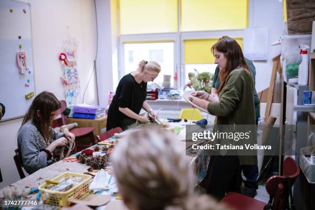 captured in midst of art therapy session, gathering of women engages in crafting christmas decorations from pinecones - art therapy stock pictures, royalty-free photos & images