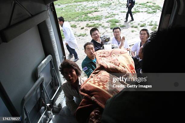 Rescuers carry an injured person onto a helicopter on July 23, 2013 in Minxian, China. At least 89 people were killed and 5 others missing after a...