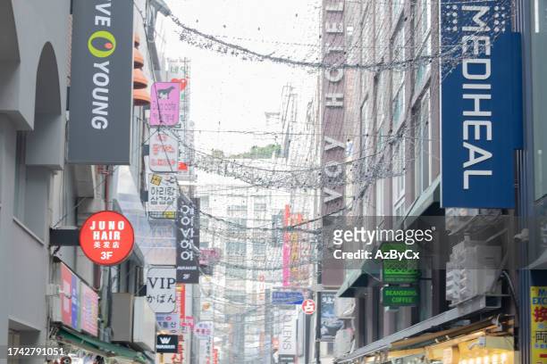 vibrant shop sign in a korean myeongdong-gil shopping street - escritura coreana fotografías e imágenes de stock