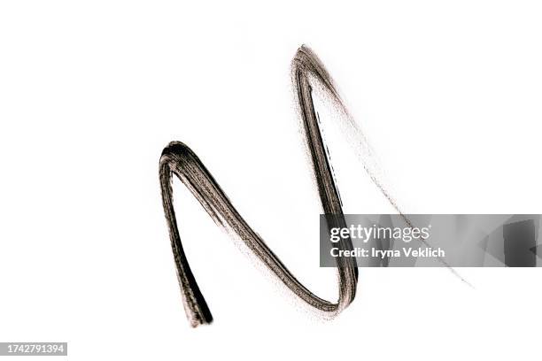waved black smear of black eyeliner pencil or eyebrow pencil on white background, isolated. cosmetic make-up product for eye and eyelashes. liquid eye liner. - kajalschminke stock-fotos und bilder
