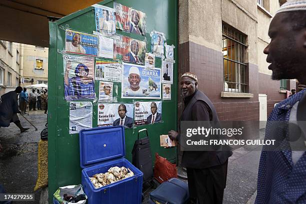 Malian people stand in front of posters displaying candidates for the upcoming presidential election in Mali on July 23, 2013 at the entrance of the...