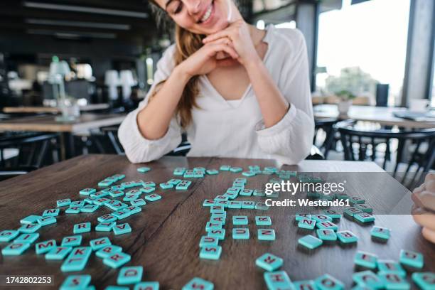 young woman playing word game at cafe table - jogo de palavras imagens e fotografias de stock