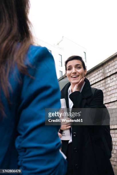 happy businesswoman talking to office friend - long coat stock pictures, royalty-free photos & images