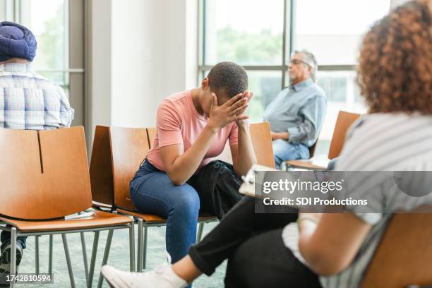 distraught woman presses hands against head while waiting for doctor - a&e stock pictures, royalty-free photos & images