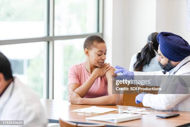 after giving woman flu shot, doctor applies bandage - free of charge stock pictures, royalty-free photos & images