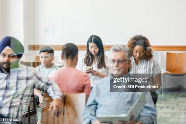 diverse group sits in clinic waiting room - hospital waiting room stockfoto's en -beelden