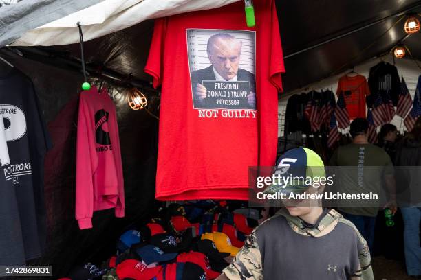 Boy looks over right wing paraphernalia being sold at a booth at the Fryeburg Fair, including a t shirt with a mug shot of former President Trump, on...