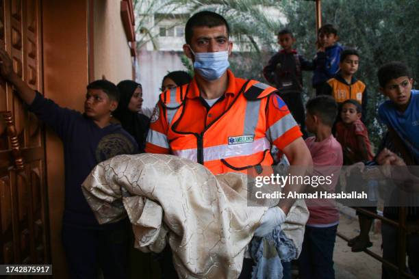 Palestinian civil defense member carries the body of a child who was killed during Israeli airstrikes on October 18, 2023 in Khan Yunis, Gaza. Gazans...