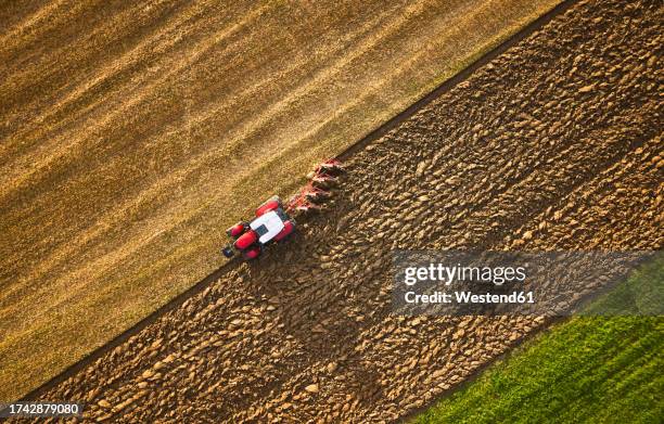 farmer using tractor and plowing land at sunrise - campo arado fotografías e imágenes de stock