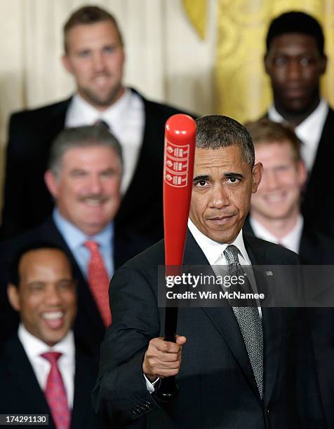 President Barack Obama waves a Louisville Slugger baseball bat presented to him by the Louisville Cardinals, the 2013 NCAA Men's Basketball...