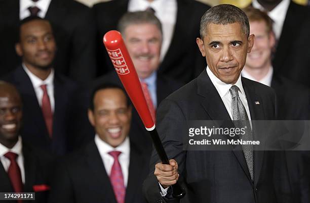 President Barack Obama waves a Louisville Slugger baseball bat presented to him by the Louisville Cardinals, the 2013 NCAA Men's Basketball...