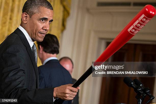 President Barack Obama holds a Louisville Slugger baseball bat given to him by Louisville coach Rick Pitino during an event in the East Room of the...