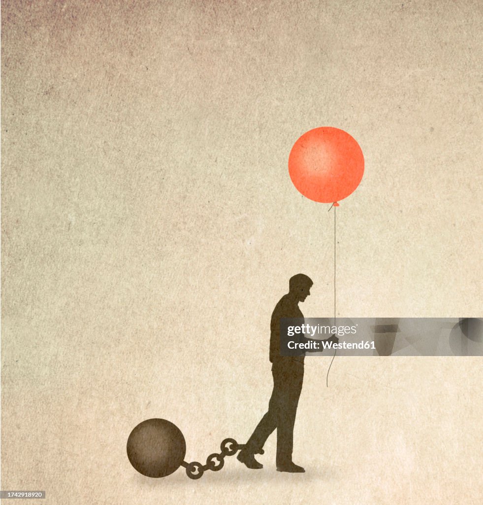 Silhouette of man restrained by ball and chain holding balloon symbolizing hope
