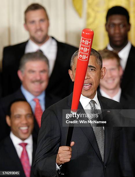 President Barack Obama waves a Louisville Slugger baseball bat presented to him by head coach Rick Pitino of the Louisville Cardinals, the 2013 NCAA...